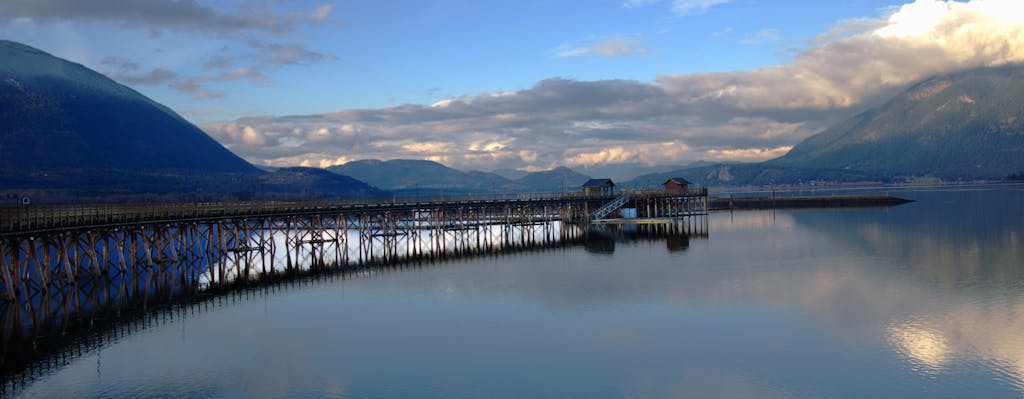 Tranquil panorama of Salmon Arm Pier with mountains and reflections at twilight.