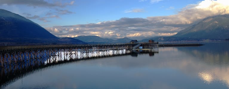Tranquil panorama of Salmon Arm Pier with mountains and reflections at twilight.